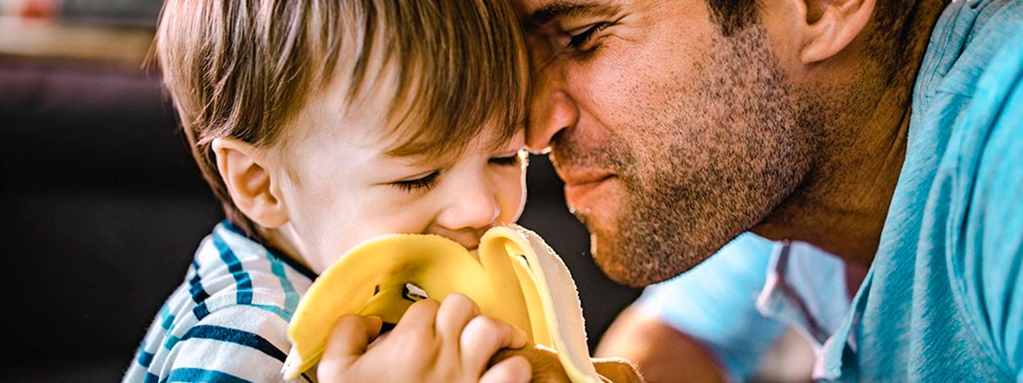 Niño comiendo plátano con su papá